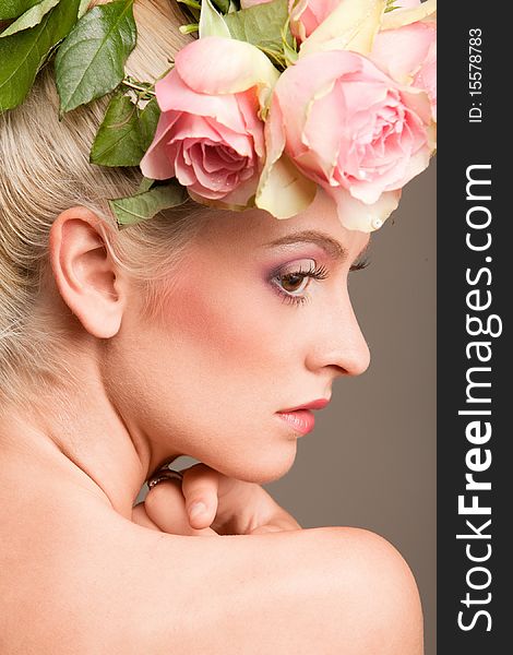 Portrait of beautiful blonde with a wreath of flowers on her head on the grey background