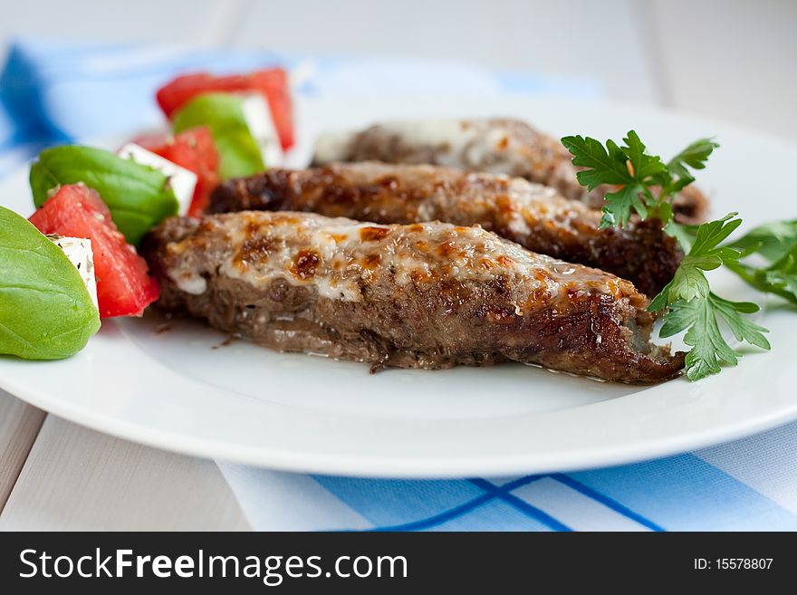 Roasted stuffed pork rolls served with tomatoes and feta