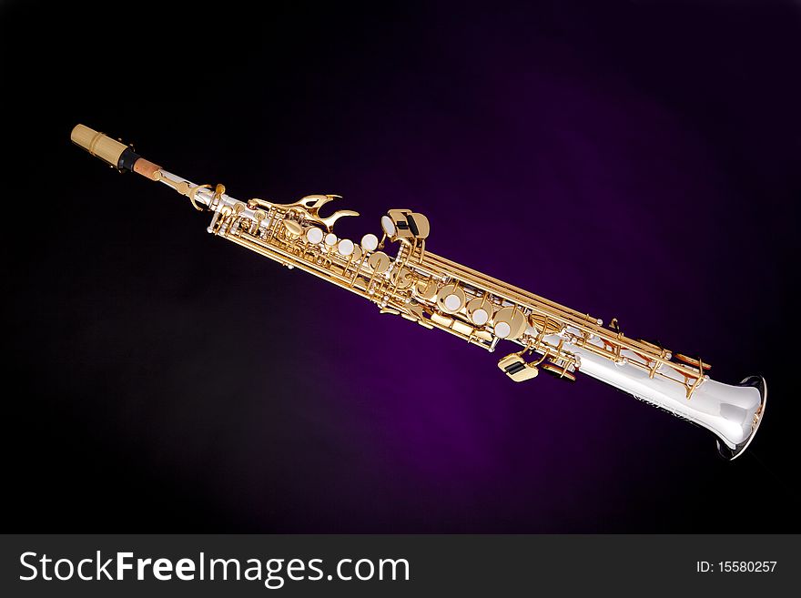 A professional soprano saxophone isolated against a spotlight purple background. A professional soprano saxophone isolated against a spotlight purple background.