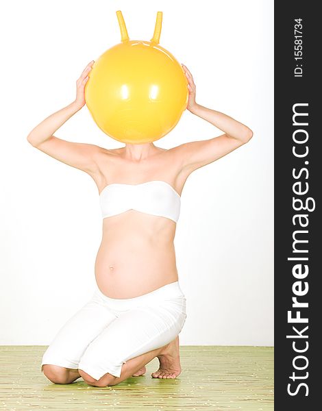 Studio portrait of pregnant woman with ball across head