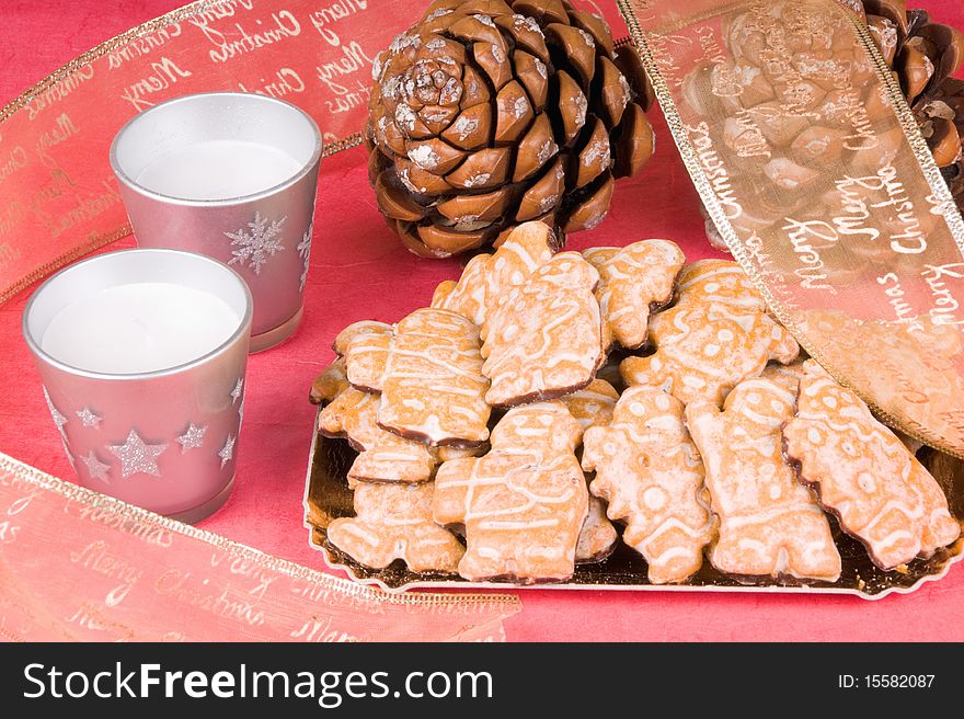 Christmas composition: gingerbread men, Christmas ribbon, pine cones and candles. Studio shot over red background. Christmas composition: gingerbread men, Christmas ribbon, pine cones and candles. Studio shot over red background