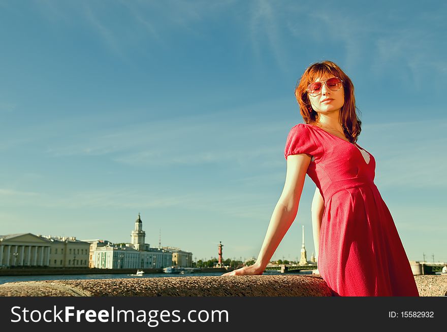 The young girl dreams on quay of the river with a kind on the bridge