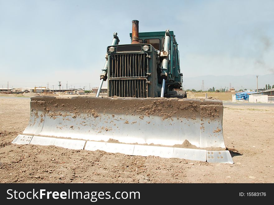 A large green bulldozer at a construction site low angle view