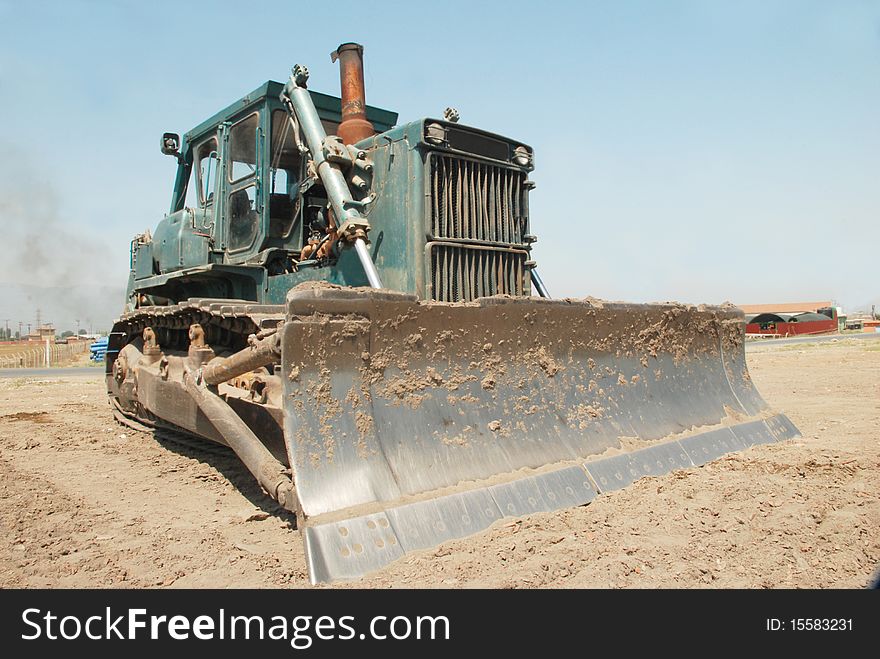 A large green bulldozer at a construction site low angle view