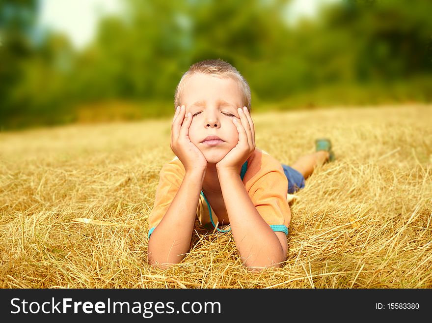 A carefree young boy laying on ground whith shutted eyes