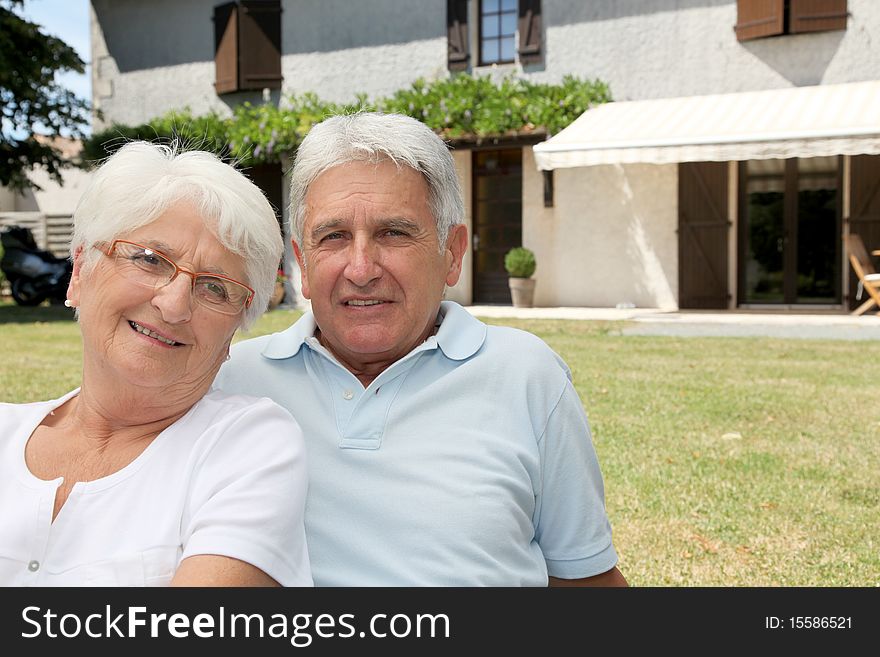 Senior couple sitting in front of a house. Senior couple sitting in front of a house