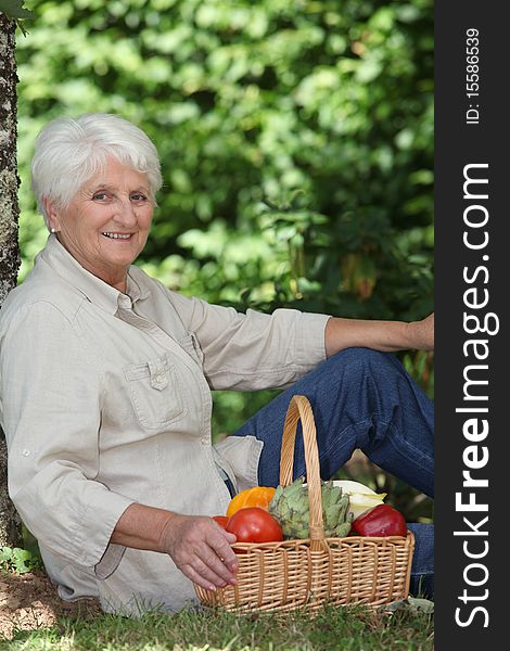 Elderly woman in garden with basket of vegetables. Elderly woman in garden with basket of vegetables