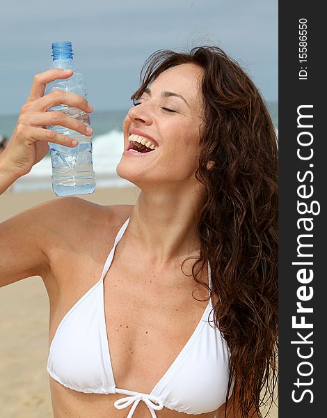 Beautiful woman drinking water at the beach. Beautiful woman drinking water at the beach