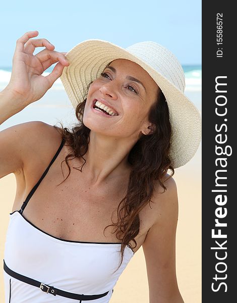 Beautiful woman sitting on the beach with straw hat. Beautiful woman sitting on the beach with straw hat