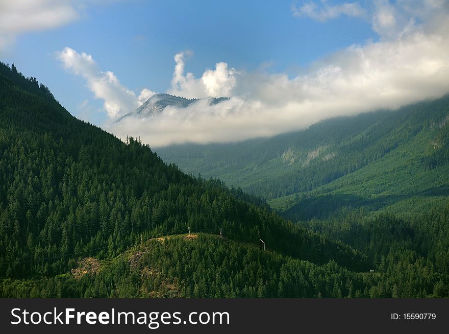 Clouds hovering over tree-covered mountains in a fine afternoon. Clouds hovering over tree-covered mountains in a fine afternoon