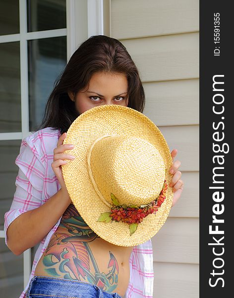 Young woman with tattoo holding hat in front of her face and chest. Young woman with tattoo holding hat in front of her face and chest