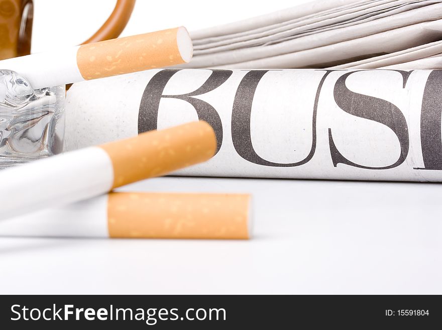 Newspaper with the word business on it laying next to an ashtray and cigarettes.