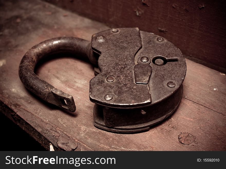 Old rusty padlock on a shelf with chipped paint closeup