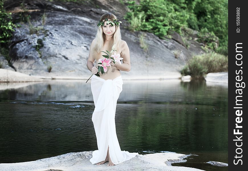 Beautiful woman as a forest nymph on the river