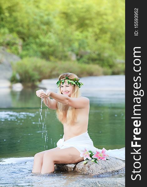 Beautiful woman as a forest nymph on the river