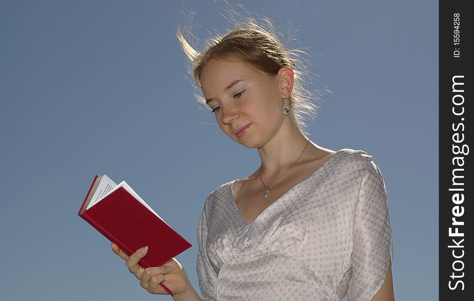 A girl reading a book with the red cover. A girl reading a book with the red cover