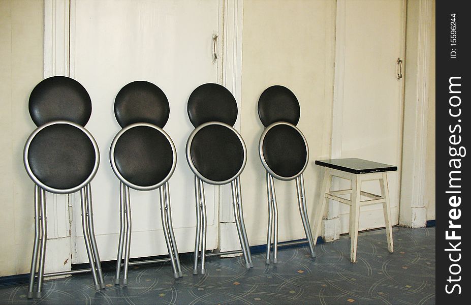 Folding chairs and stool against a white wall