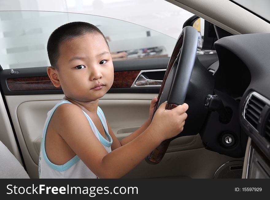 A Chinese boy inside a new car gestures to drive. A Chinese boy inside a new car gestures to drive.