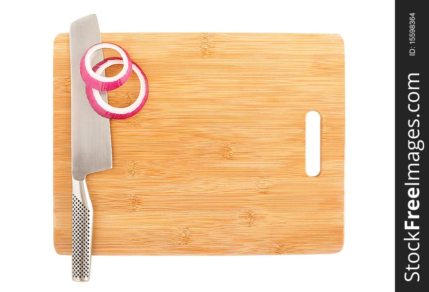 Slices of cut onion and a stainless chef's knife on a board. Slices of cut onion and a stainless chef's knife on a board