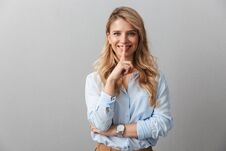 Photo Of Adorable Blond Businesswoman With Long Curly Hair Smiling And Holding Fingers At Her Mouth Stock Photos