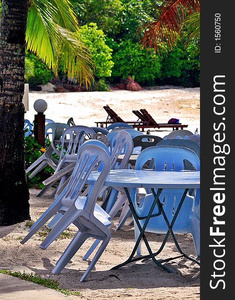 Plastic tables & chairs by the beach for dining at night.