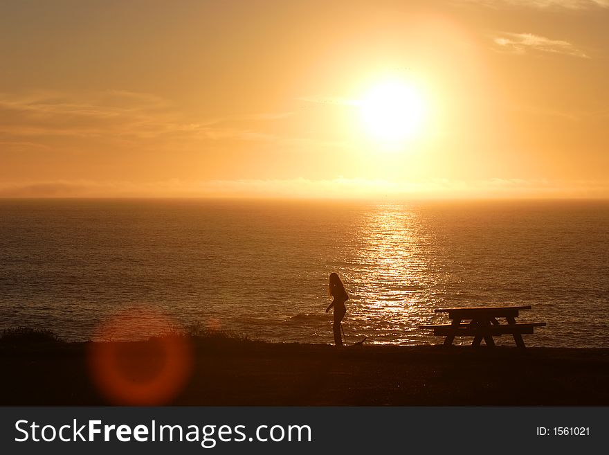 A girl walks along the sea cliffs at sunset. A girl walks along the sea cliffs at sunset