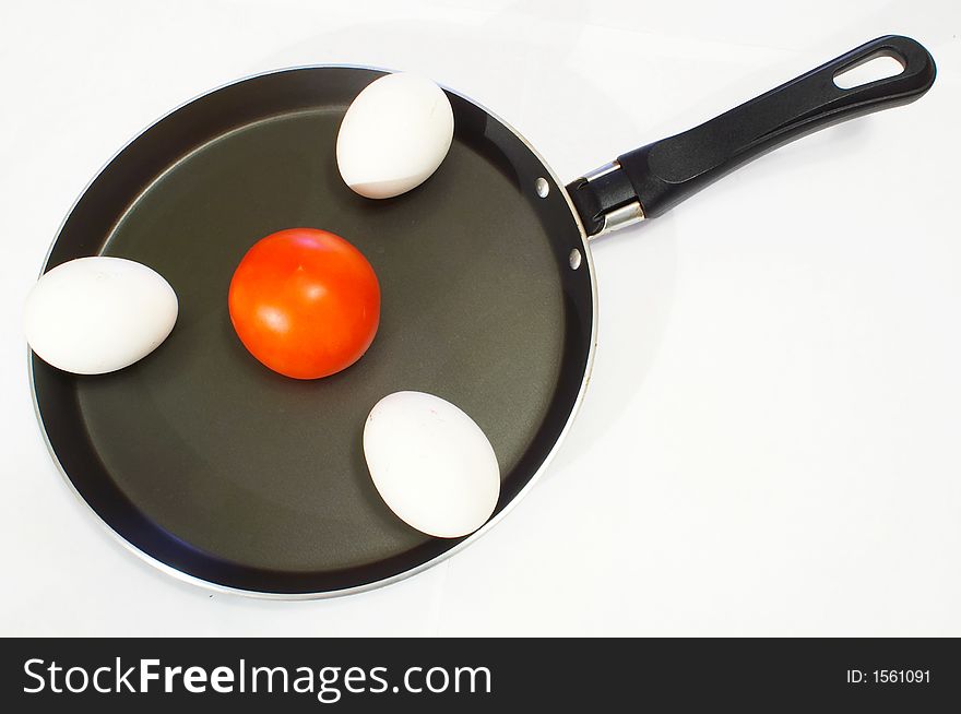 Three white chicken eggs and tomato on a frying pan for an omelet. Three white chicken eggs and tomato on a frying pan for an omelet