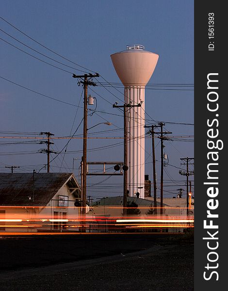 Water tower stands tall as cars zoom by at dusk