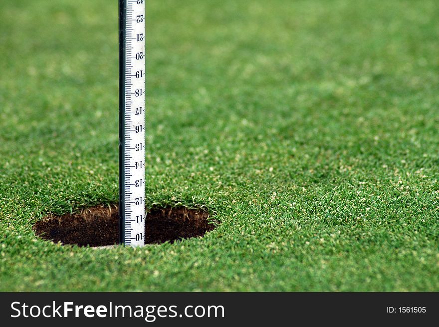 Green grass course, hole with white post. Green grass course, hole with white post