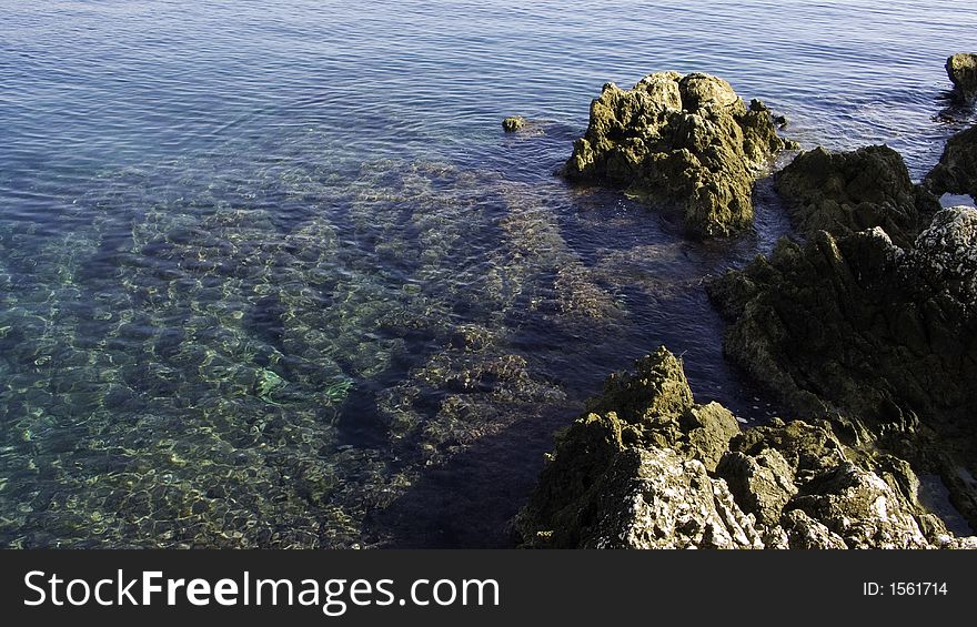 Seascape of transparent water lapping around sharp rocks. Seascape of transparent water lapping around sharp rocks