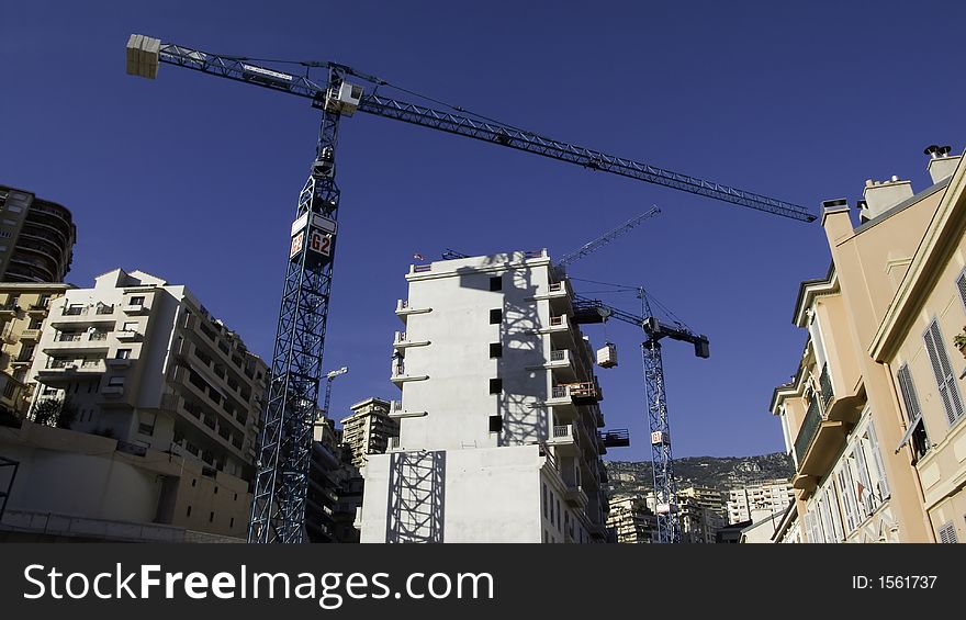 Construction building cranes against an azur blue sky