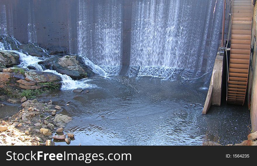 Water flowing over a dam that powers a water wheel and mill. Water flowing over a dam that powers a water wheel and mill
