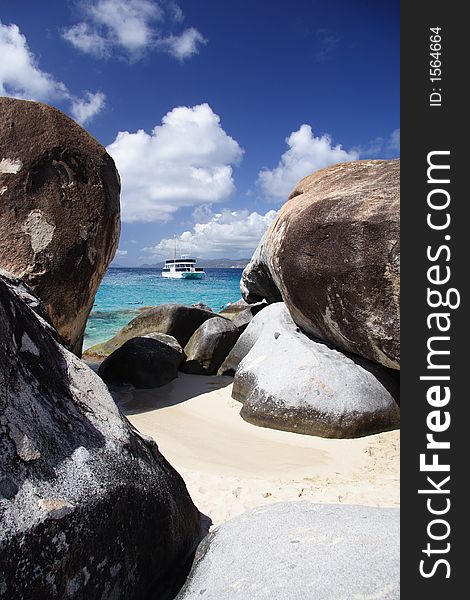 Granite rocks on a tropical beach with a boat in the background. Granite rocks on a tropical beach with a boat in the background