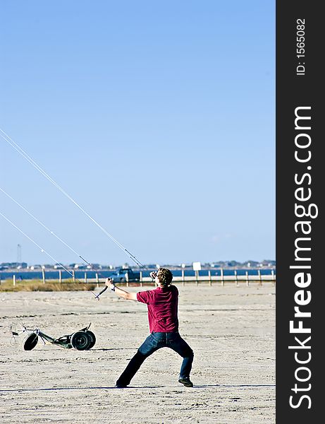 Man on the beach struggling to keep his large kit in the air. Man on the beach struggling to keep his large kit in the air.