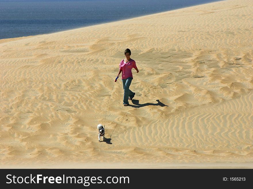 Girl walks dog on a sand dune