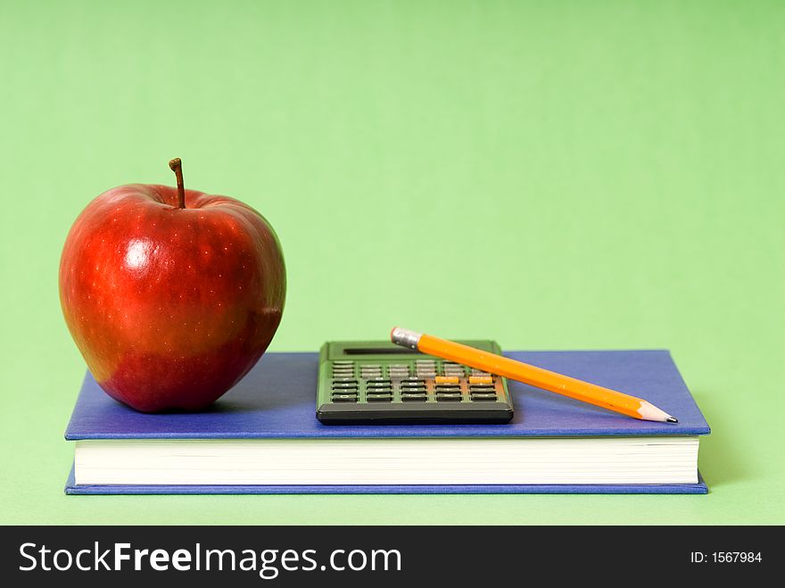 Blue book and red apple and pencil and calculator. Blue book and red apple and pencil and calculator