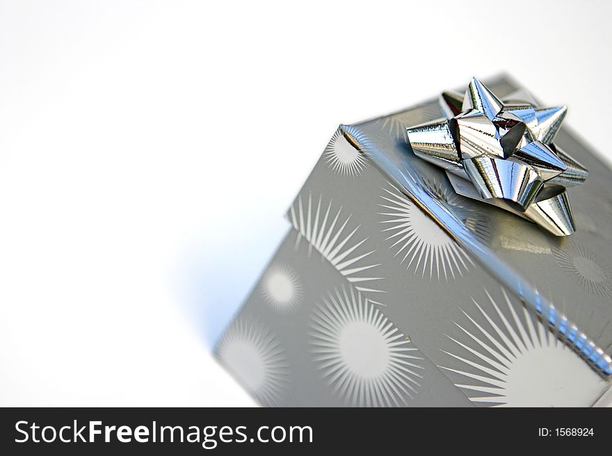 Silver wrapped present & bow isolated against white. Silver wrapped present & bow isolated against white