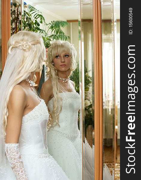 The beautiful bride looks in a mirror.