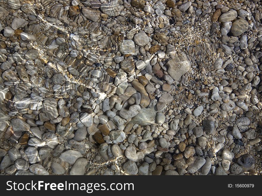 The shallow water of the Black Sea with scatter from the pebbles in the crystal clear water. The shallow water of the Black Sea with scatter from the pebbles in the crystal clear water