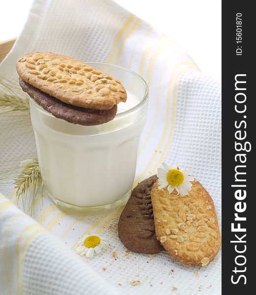 Glass of milk and cookies on light kitchen towel