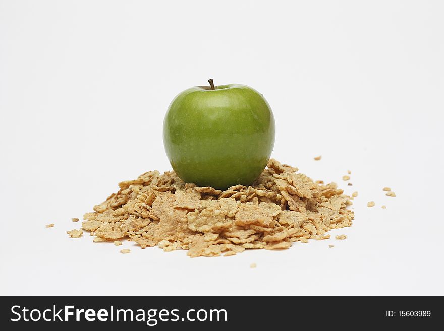 Green apple on the top of a heap of cereals isolated on white background. Green apple on the top of a heap of cereals isolated on white background