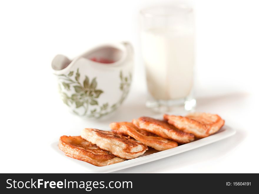 Pancakes on plate isolated on white. Sauceboat with sauce and milk behind. Pancakes on plate isolated on white. Sauceboat with sauce and milk behind