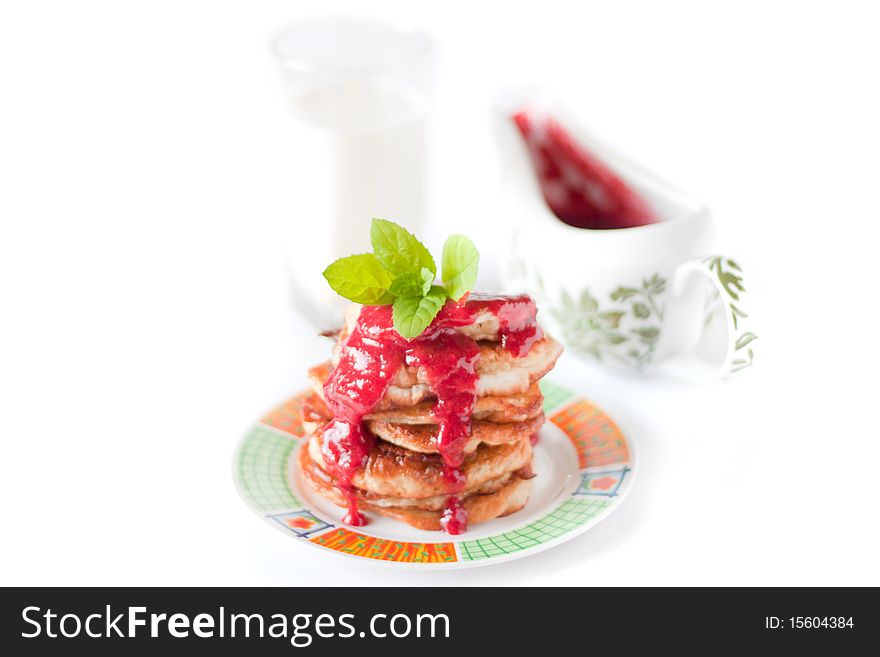 Pancakes with fresh raspbery sauce and mint isolated on white. Sauceboat with sauce behind