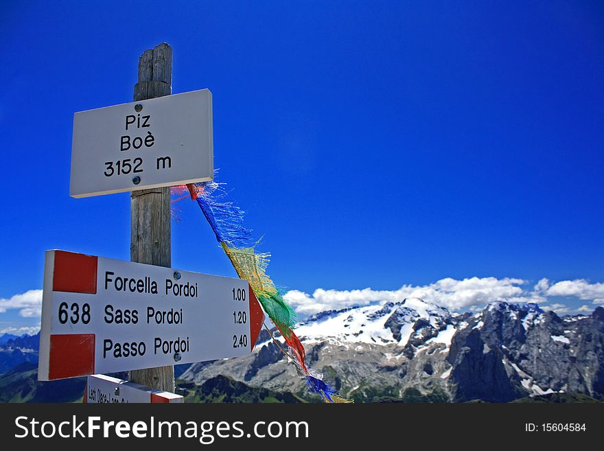 A footpath signpost on the summit of Piz Boa in the Italian alps with Marmolada in the background