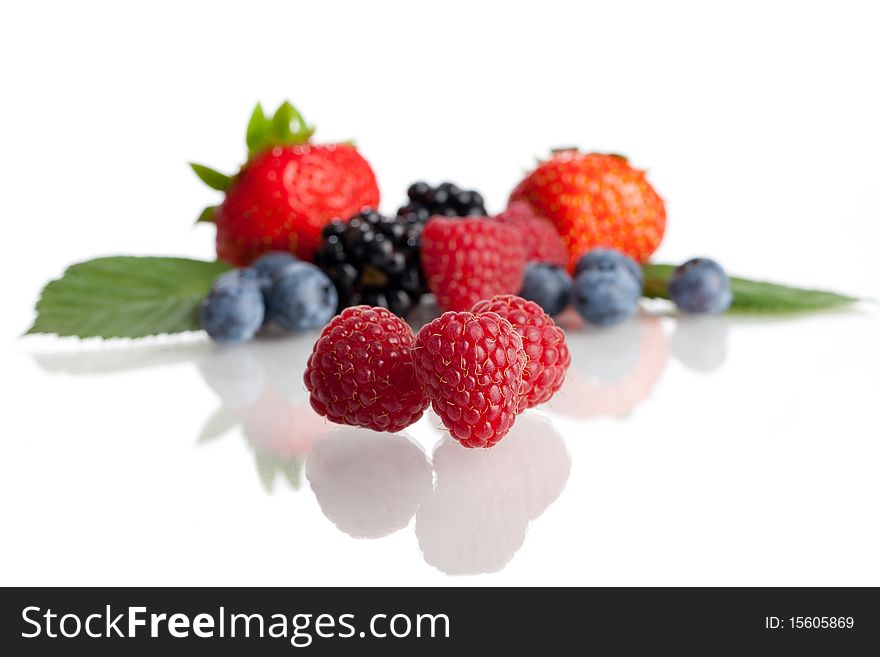 A collection of berries isolated on a white background - the focus is on the raspberries in the foreground. A collection of berries isolated on a white background - the focus is on the raspberries in the foreground