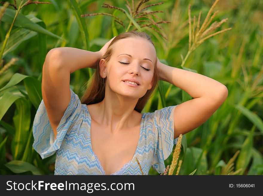 Young girl on a background of green maize and blue sky