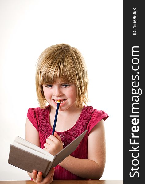 A vertical image of a cute little girl holding her diary and pencil and looking very thoughtful. A vertical image of a cute little girl holding her diary and pencil and looking very thoughtful
