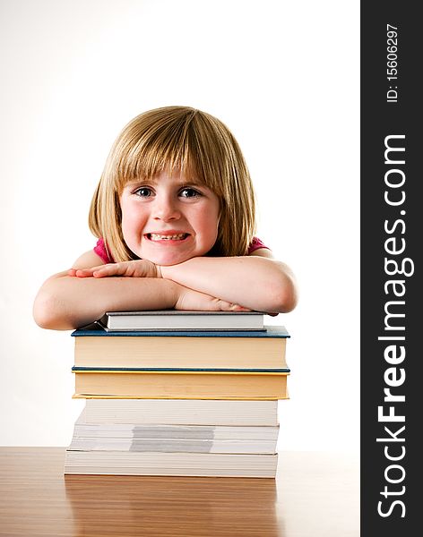 A vertical image of a cute little blonde girl leaning on a stack of books and smiling. A vertical image of a cute little blonde girl leaning on a stack of books and smiling