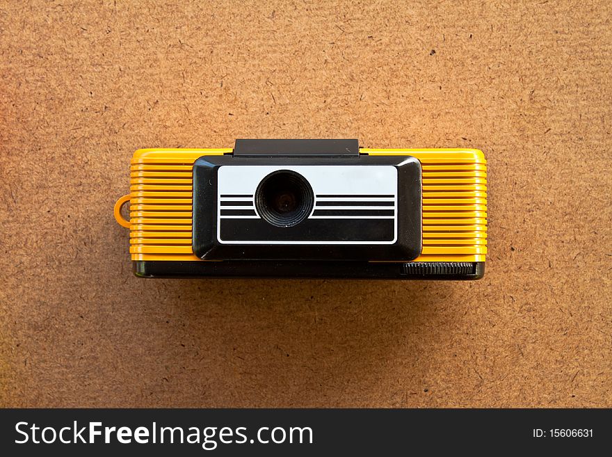 Retro yellow toy camera on wood board
