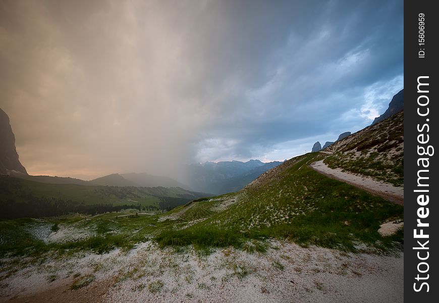 Rain approaching colored by the warm glow of sunset, the Dolomites, Italy. Rain approaching colored by the warm glow of sunset, the Dolomites, Italy